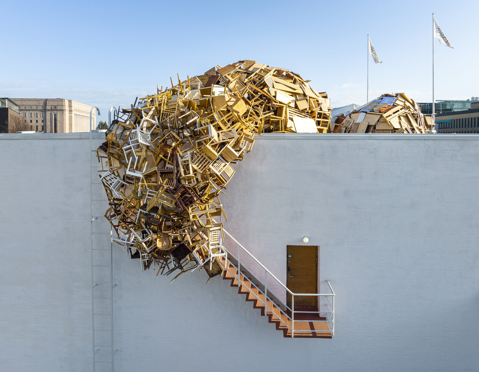 Chairs intersect each other, falling from a roof, connecting the roof to a staircase.