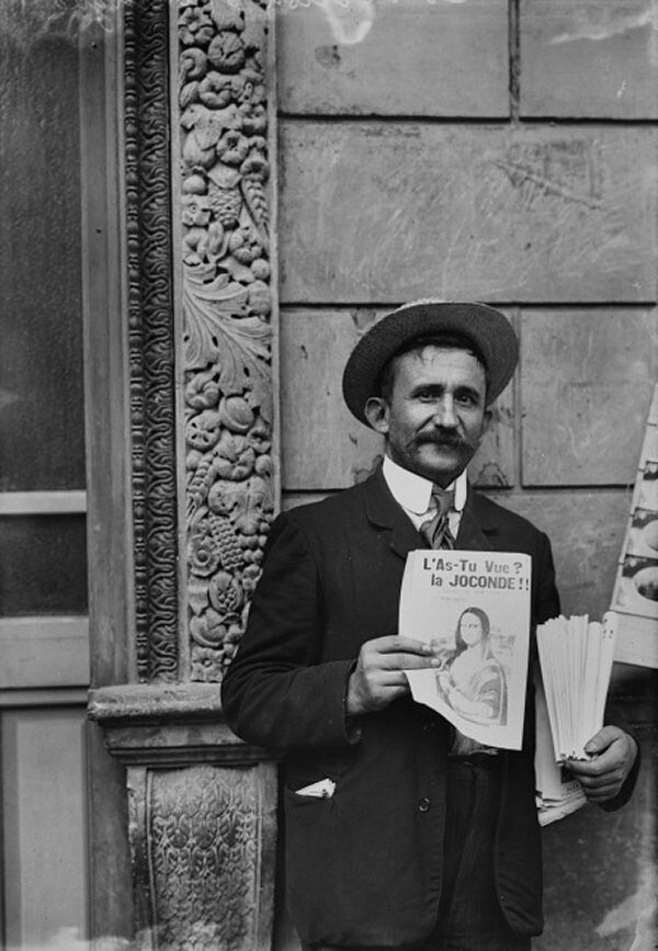 Black and white, a man with a mustache holding a flier.